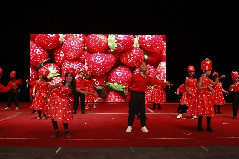 Kindergarten children dancing in strawberry costumes